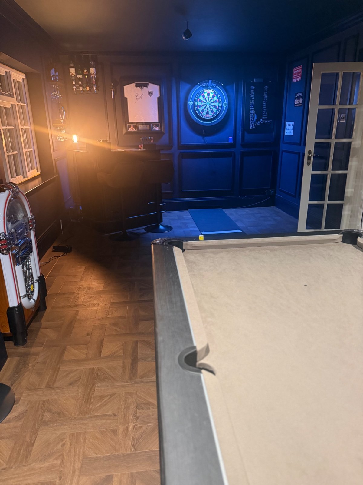 Finished navy panelled games room with pool table and dartboard, wide shot