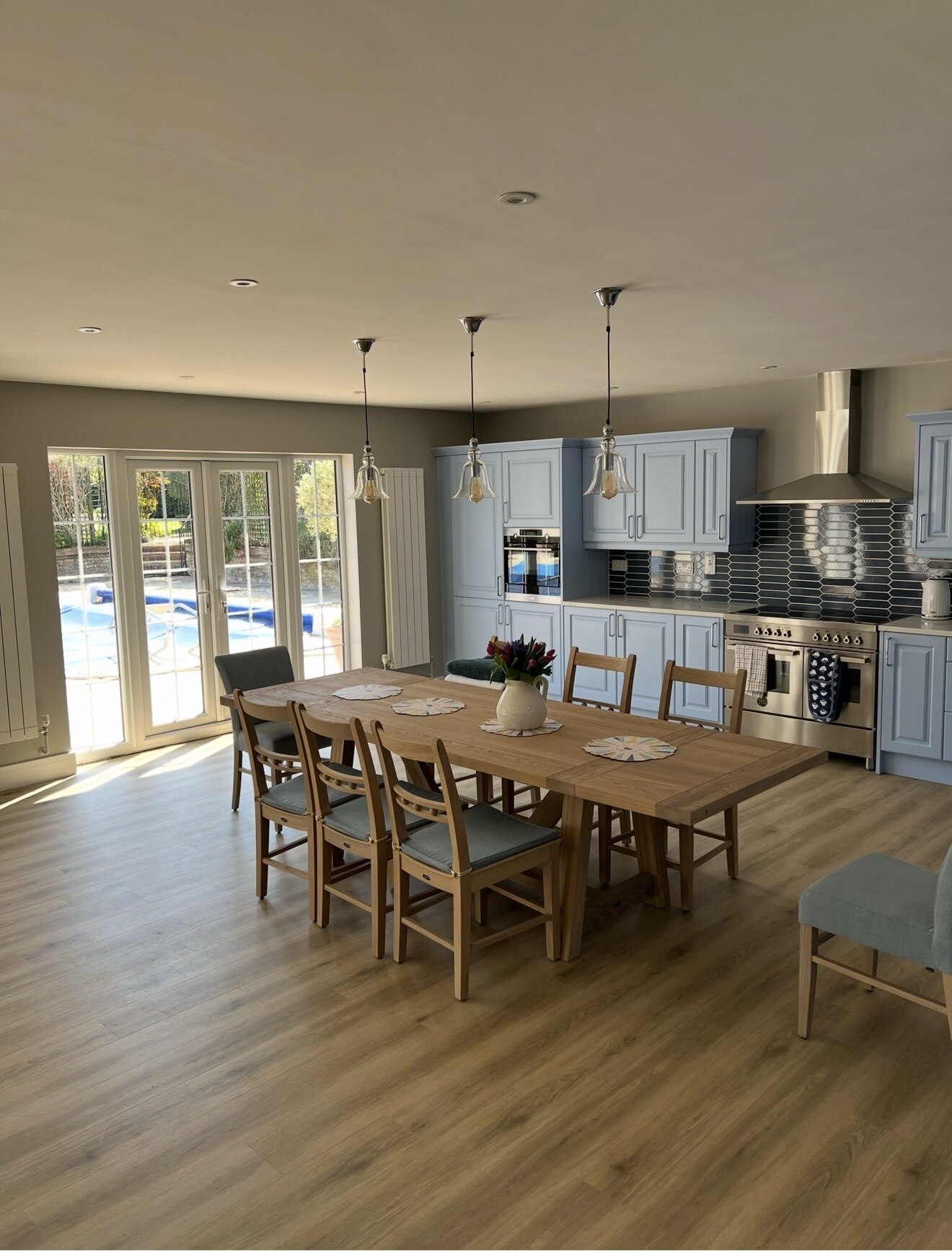 Create Solutions blue kitchen-diner with a timber dining table and glazed garden doors