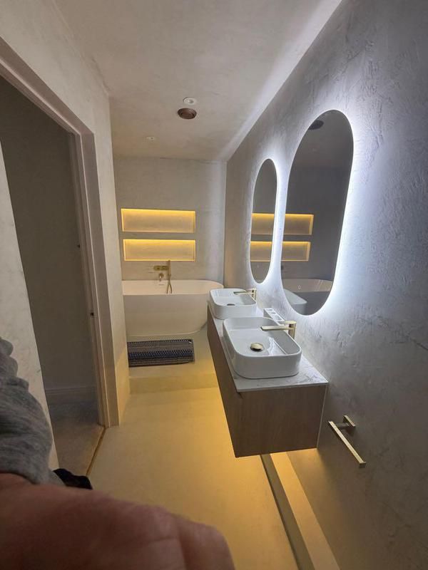 Doorway view of the bathroom with illuminated mirrors and niche lighting