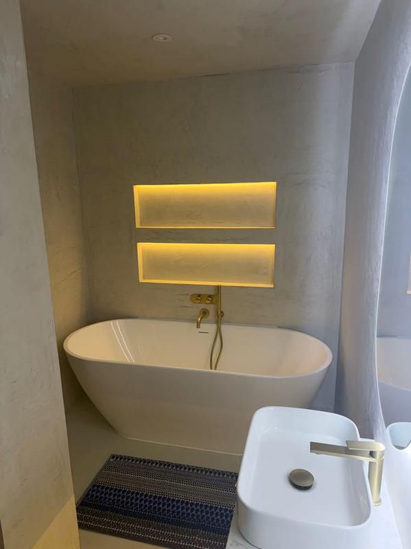 Freestanding bath beneath illuminated recessed shelves
