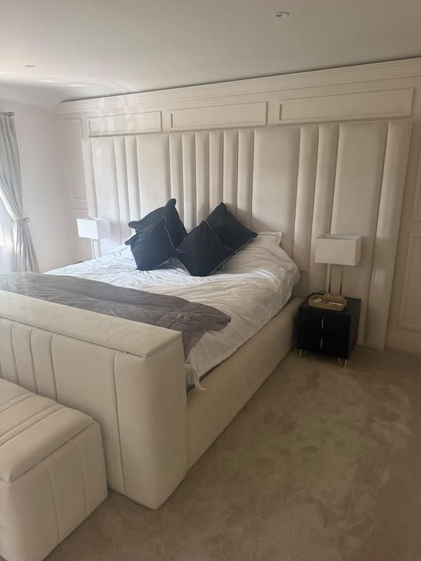 Angled view of the cream panelled headboard wall and bed