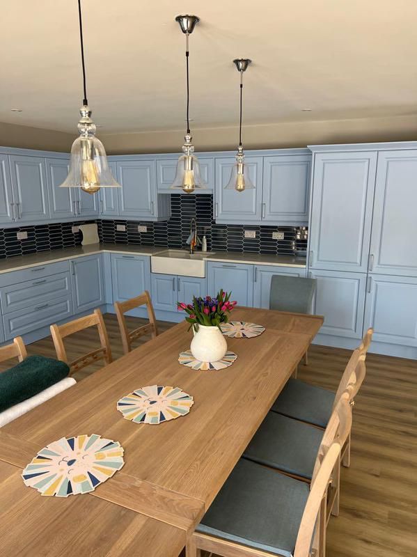 Pendant lights above the dining table and blue kitchen units