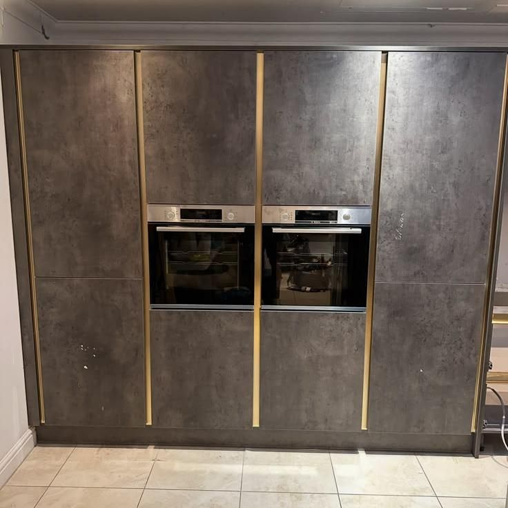 Tall concrete-effect units housing two ovens with brass trim