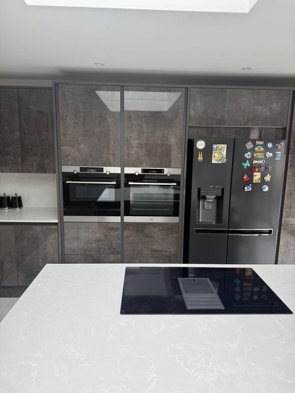 White island with induction hob in front of grey tall units