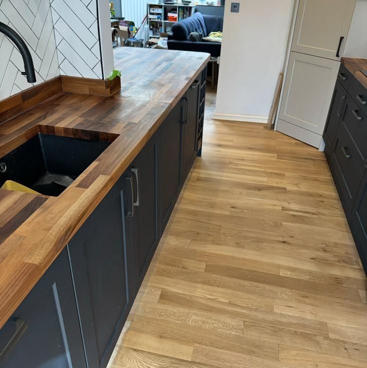 Undermounted sink in a long timber worktop over dark units