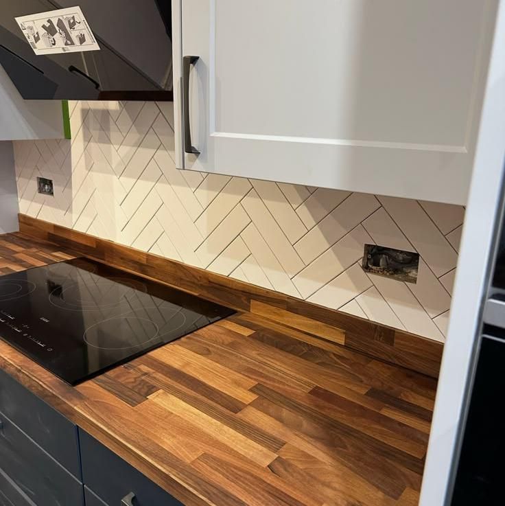 Induction hob set into a timber worktop with herringbone tiles