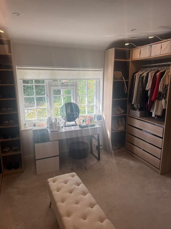 Dressing table beneath a window beside fitted wardrobes