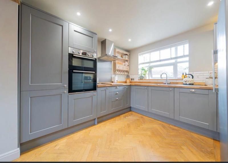 L-shaped grey shaker kitchen with timber worktops and herringbone floor