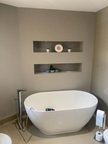 Freestanding bath beneath two recessed shelving niches