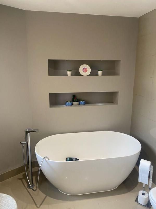 Freestanding bath beneath two recessed shelving niches