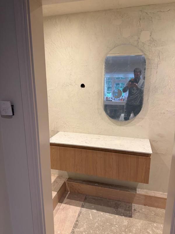 Wall-hung timber vanity beneath an illuminated mirror