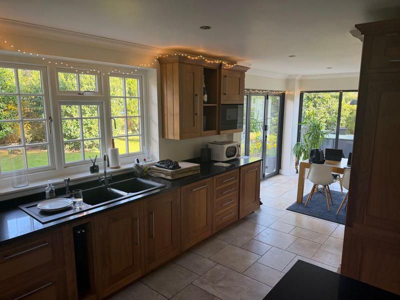 Oak kitchen with dark worktops looking onto a garden room