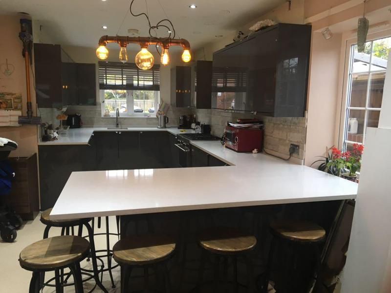 Dark gloss kitchen with a white breakfast bar and stools
