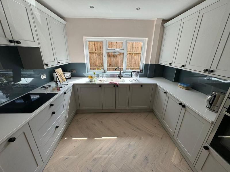 U-shaped light grey kitchen with a black splashback