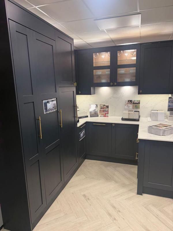 Dark shaker showroom display with glazed wall units and herringbone floor