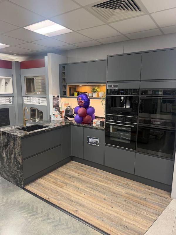 Corner showroom display with dark units and built-in ovens