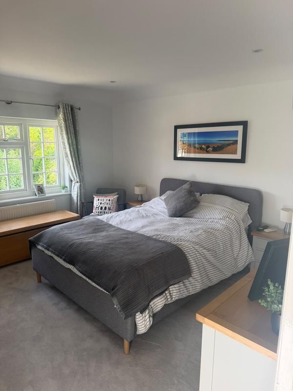 Bedroom with a grey bed beside a window and built-in window seat
